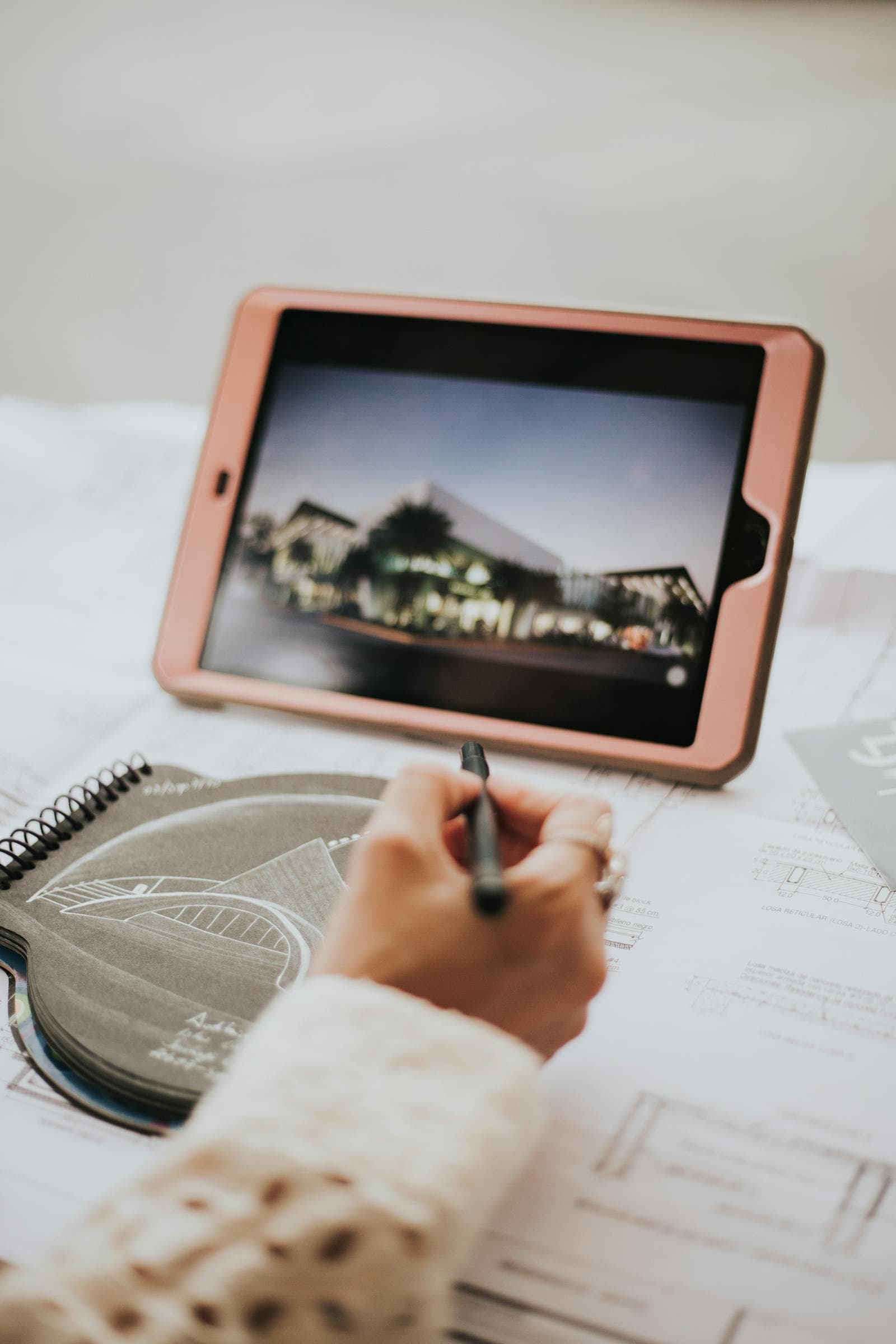 Architektin arbeitet mit Tablet und Bauplan an einem hellen Schreibtisch